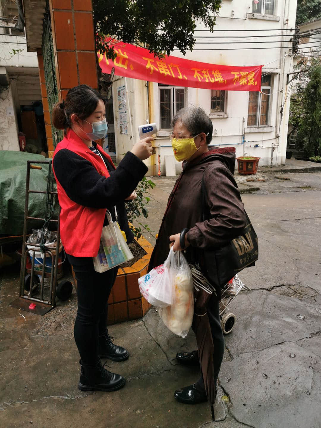 党员志愿者冒雨为社区居民测温