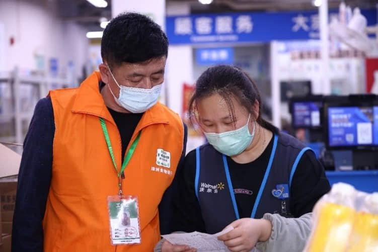 配图说明:沃尔玛员工在与绿洲志愿者进行余量食物捐赠交接